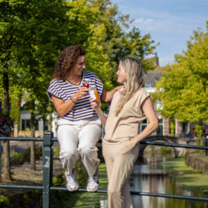 two women sitting on a railing holding bottles